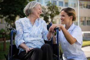 Two senior residents talking calmly with a community staff member in a bright common room.