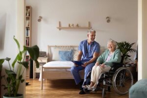 Older adult speaking with a caregiver in a bright assisted living apartment while family members visit